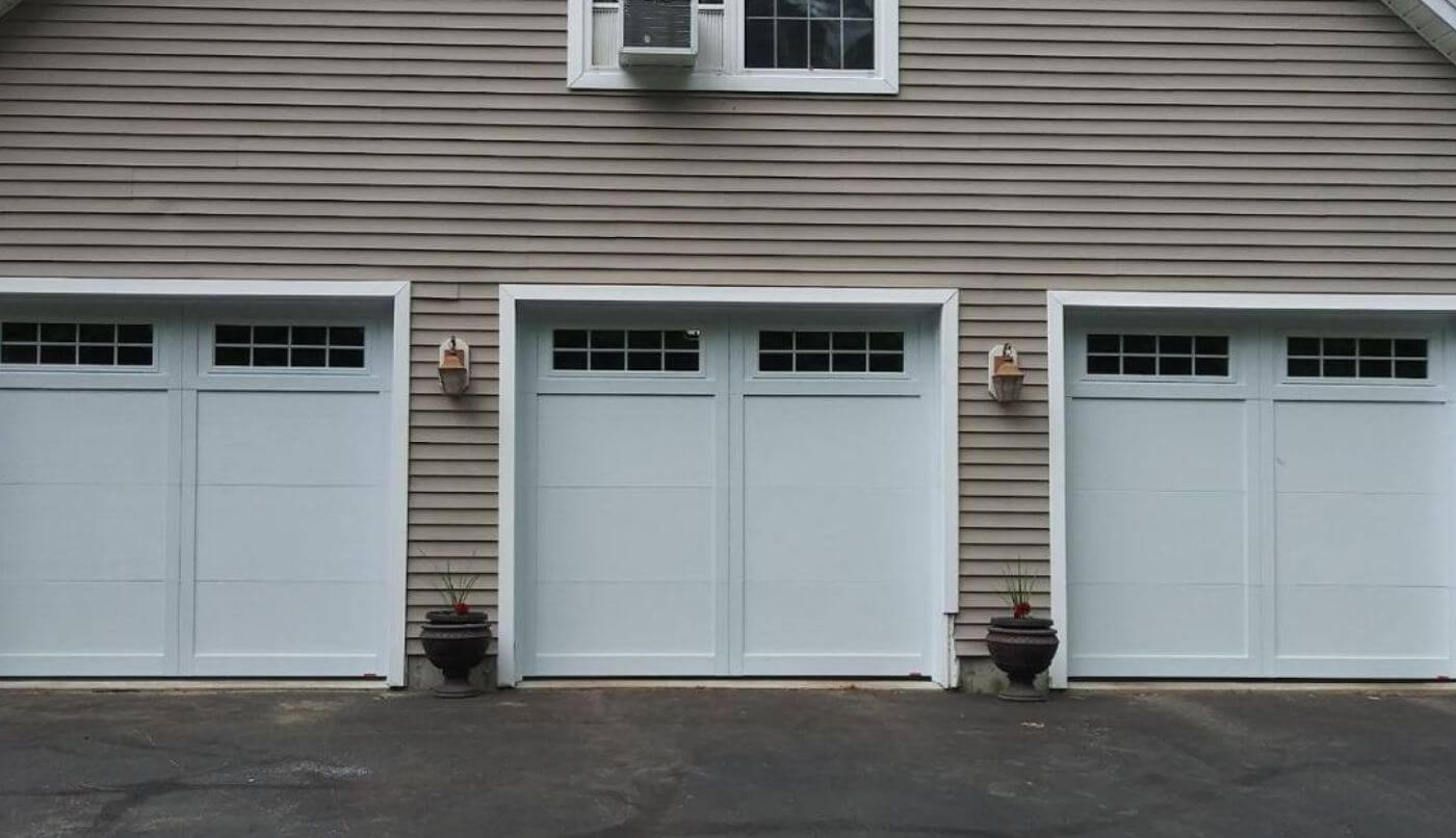 The image depicts a house with three white garage doors, contributing to its overall architectural design.