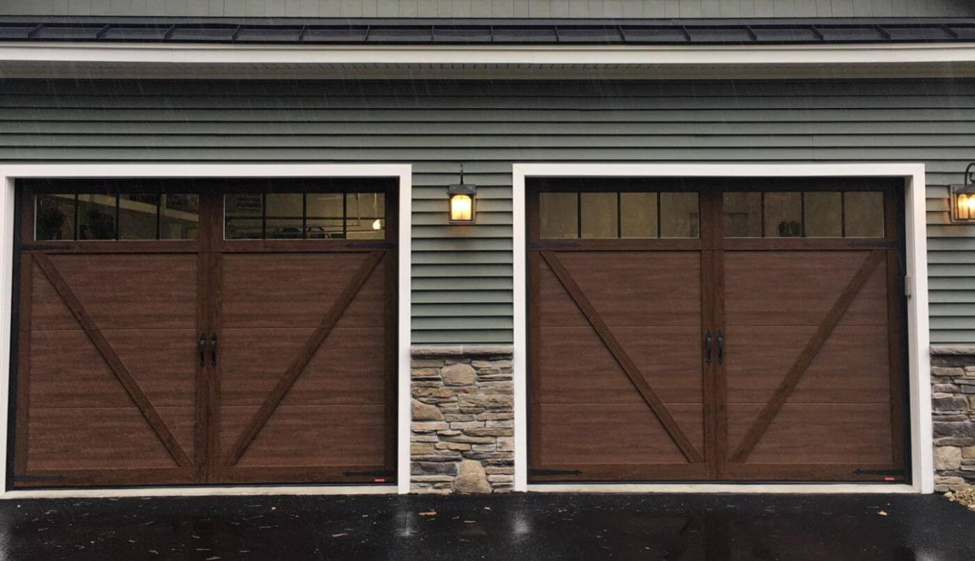 Two brown garage doors flanked by lights, set against the exterior of a house, creating a welcoming appearance.